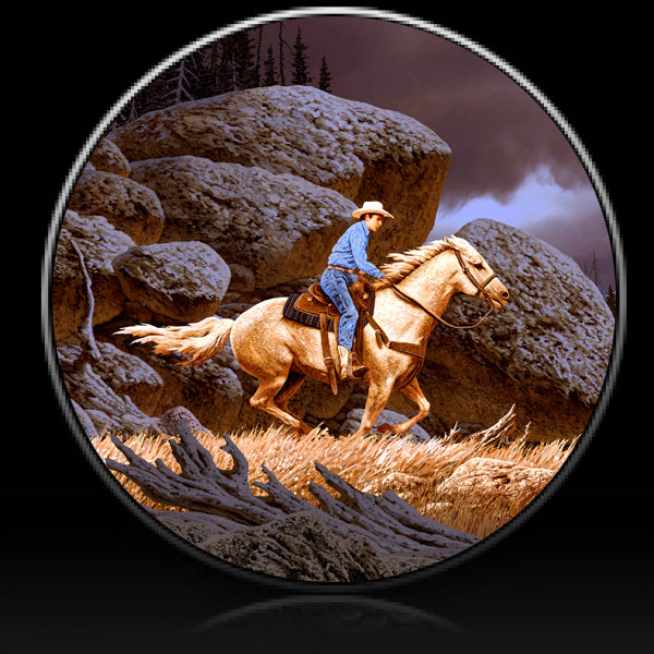 Horse and cowboy riding thru rocky scene spare tire cover